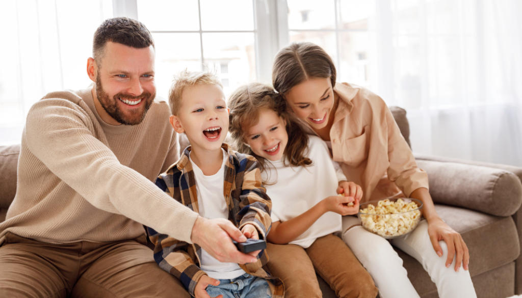 Family sitting on a couch eating popcorn and laughing together