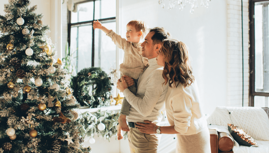 Young family smiling and pointing at a decorated Christmas tree