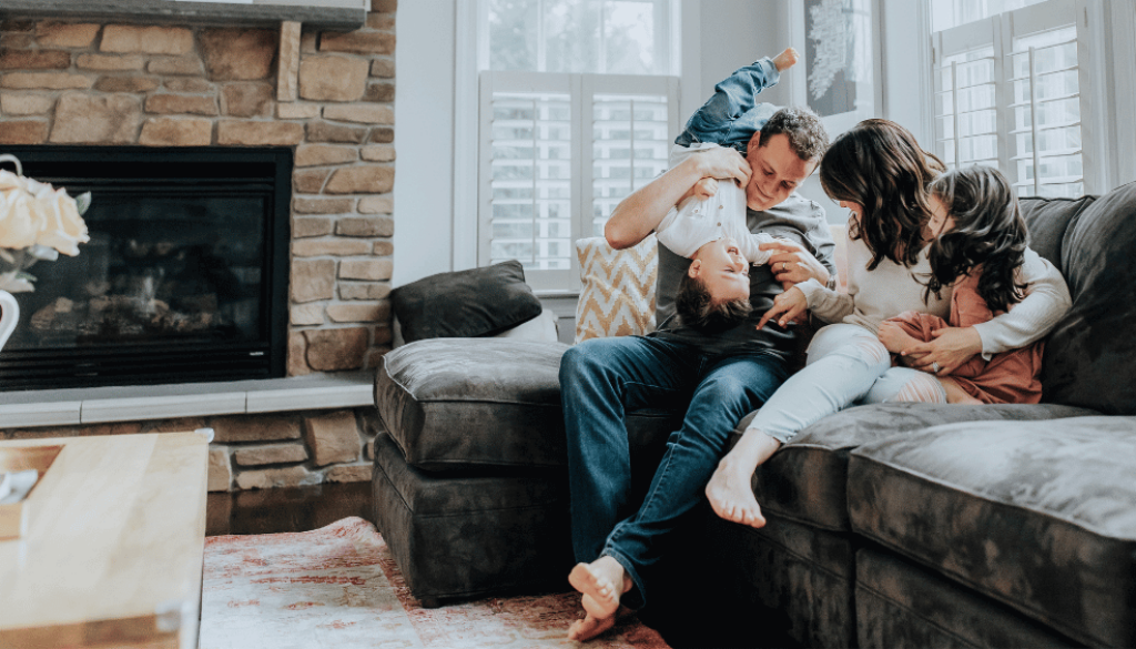 Family laughing while sitting on the couch in their living room